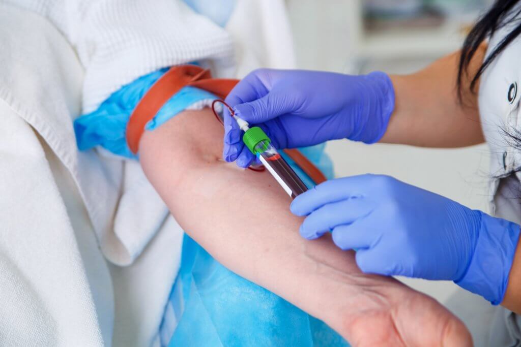 person performing phlebotomy on a patient